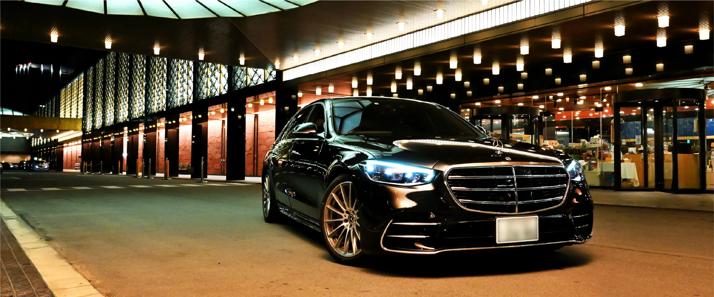 夜の街並みを背景に停車するメルセデス・ベンツ